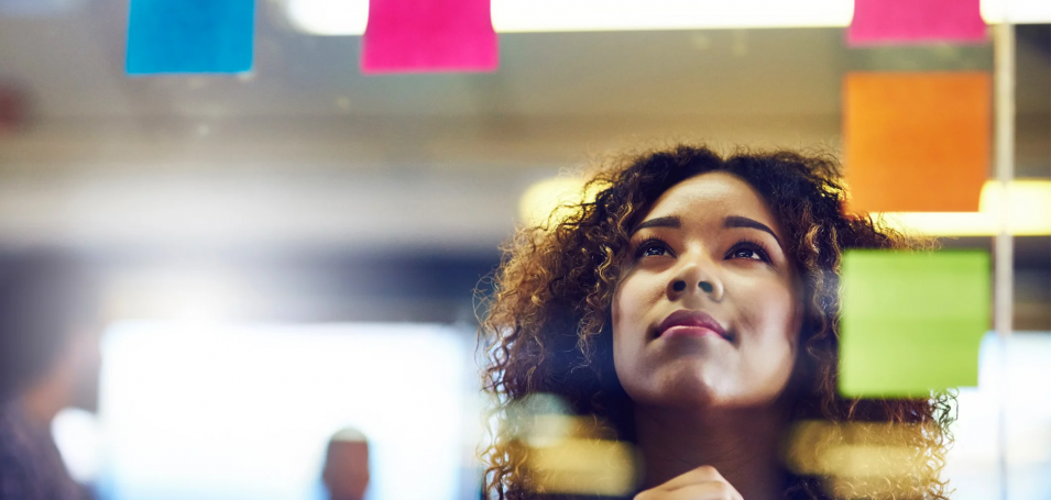 Woman looking at sticky notes on a clear board