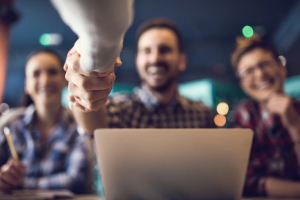Man shaking someones hand over a laptop