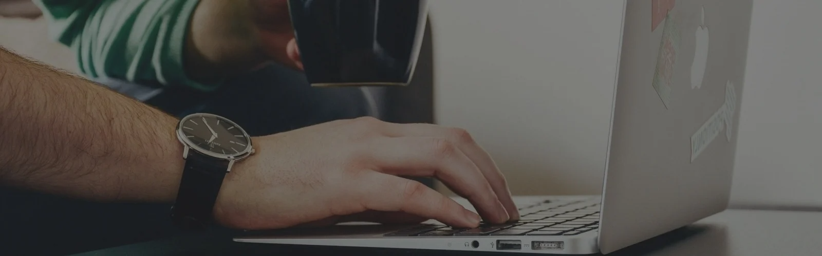 Person with watch on typing on a laptop