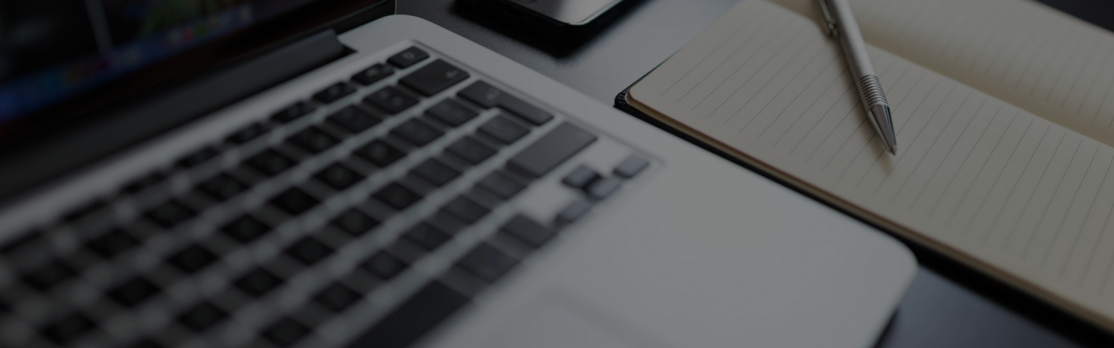 Keyboard on a laptop next to a notebook