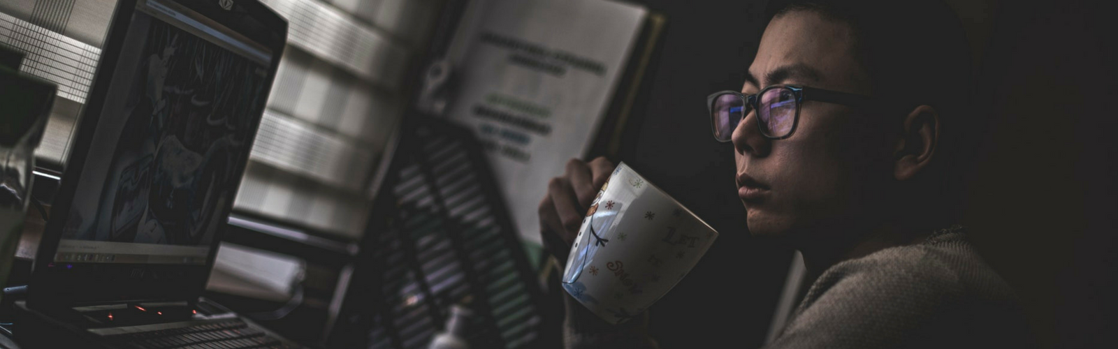 Person holding a coffee cup looking at a computer
