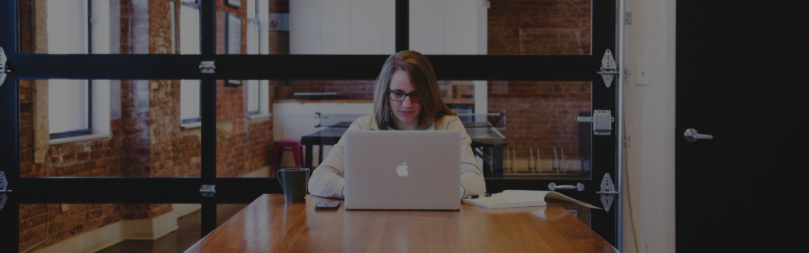 Woman sitting at the end of a table on a laptop