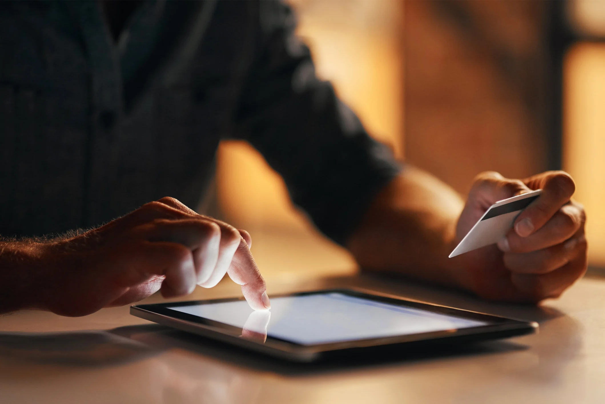 Hand holding a card typing on a tablet